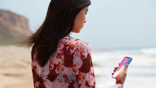 femme et iPhone X sur la plage