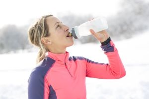 femme sportive buvant de l'eau pendant son footing dans le froid