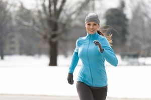 femme pratiquant la course à pied dans le froid sur un chemin couvert de neige